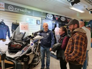 Three people standing in front of a motorcycle.